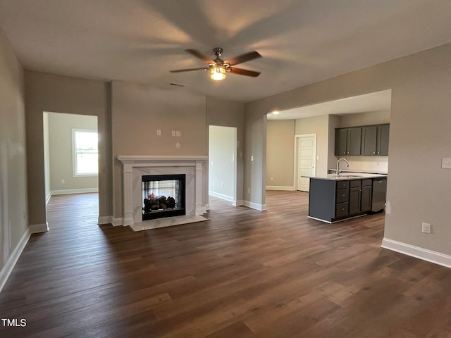 unfurnished living room with dark hardwood / wood-style flooring, ceiling fan, sink, and a high end fireplace