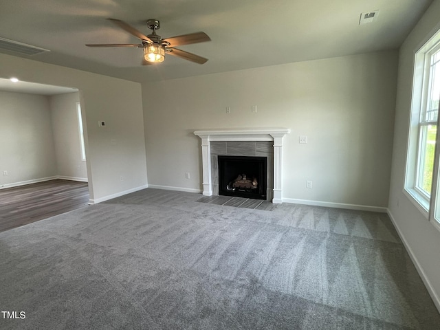 unfurnished living room featuring a tiled fireplace, ceiling fan, and carpet floors