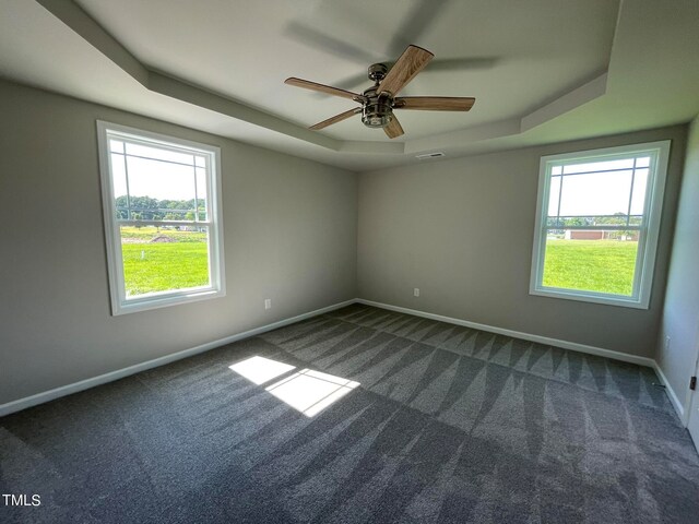 carpeted empty room with ceiling fan and a tray ceiling