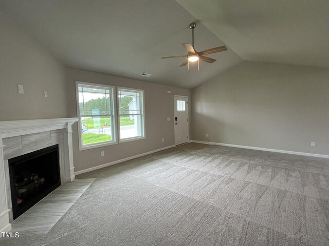 unfurnished living room with carpet flooring, lofted ceiling, a tile fireplace, and ceiling fan