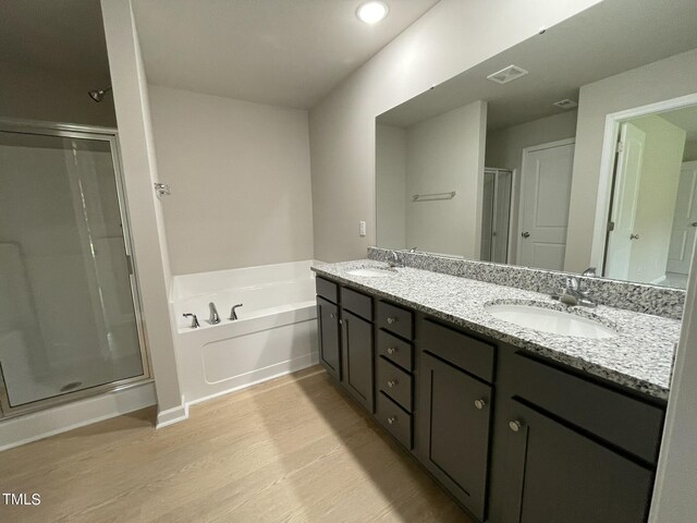 bathroom with plus walk in shower, wood-type flooring, and double sink vanity