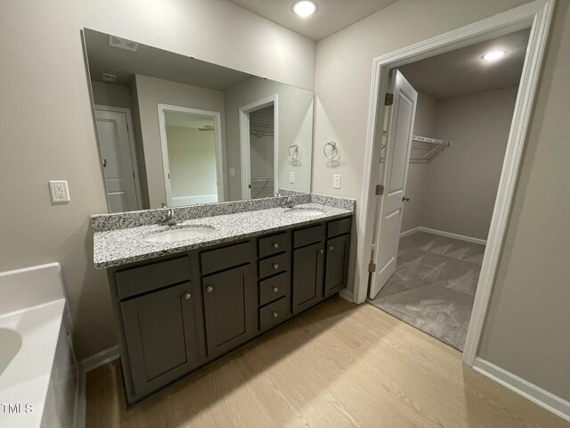 bathroom with a washtub, wood-type flooring, and dual bowl vanity