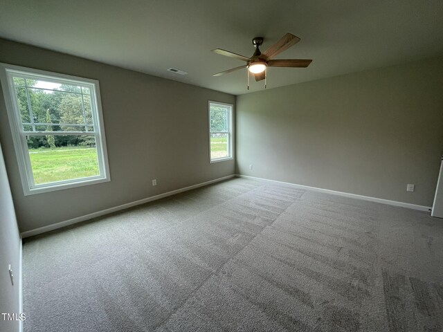 carpeted empty room with ceiling fan and plenty of natural light