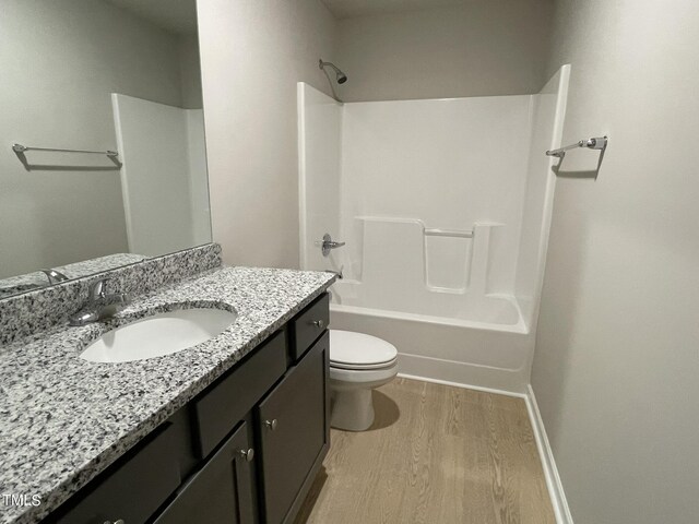 full bathroom featuring vanity, washtub / shower combination, hardwood / wood-style flooring, and toilet