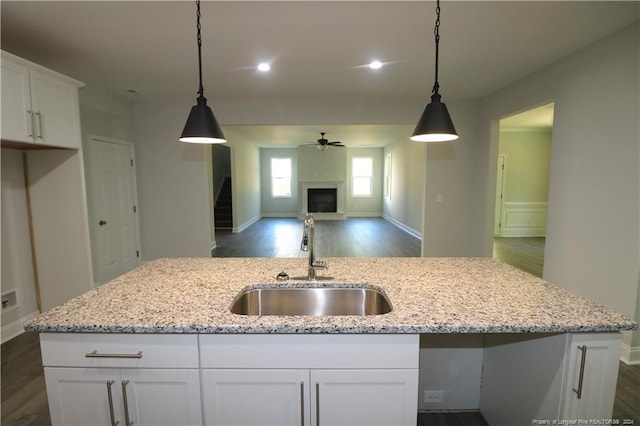 kitchen with white cabinets, dark wood-type flooring, sink, and light stone countertops