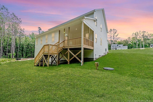 back house at dusk featuring a lawn and a wooden deck