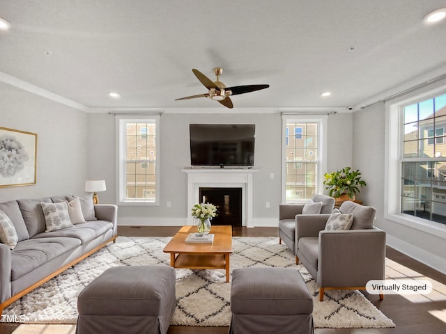 living room featuring ceiling fan, ornamental molding, a wealth of natural light, and light hardwood / wood-style floors