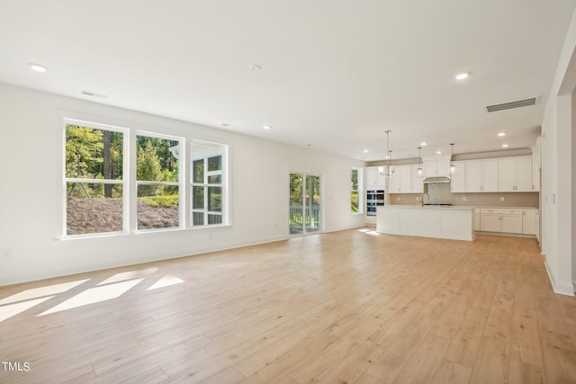 unfurnished living room with a wealth of natural light, sink, and light hardwood / wood-style floors