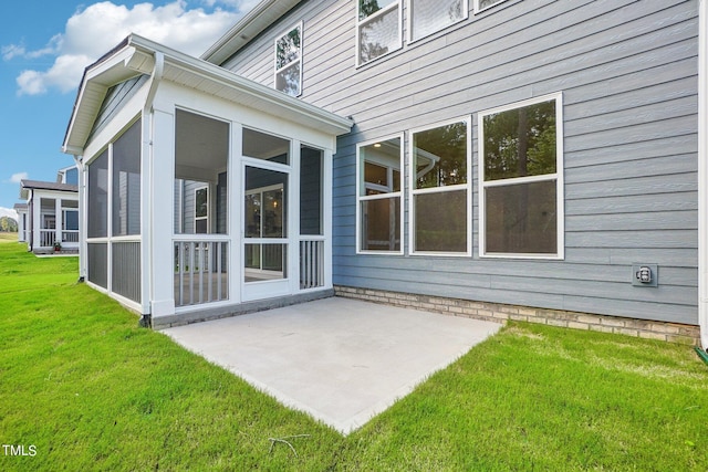 rear view of house with a patio area, a sunroom, and a lawn