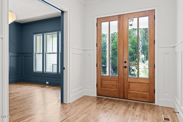 doorway to outside featuring french doors, light wood-type flooring, and crown molding