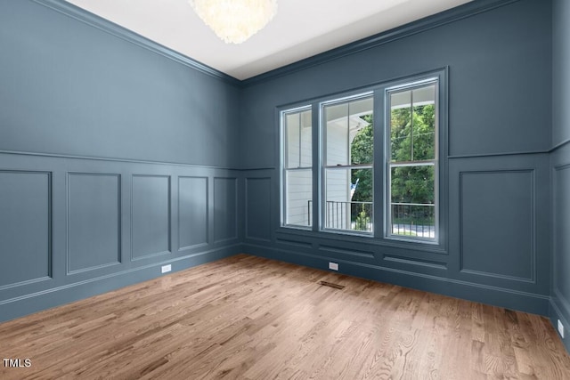 unfurnished room featuring a notable chandelier, light wood-type flooring, and ornamental molding