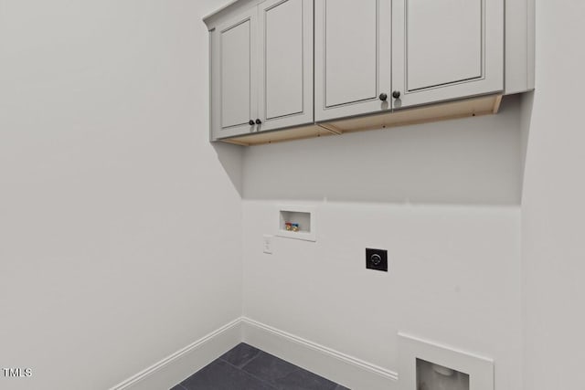 laundry area with electric dryer hookup, hookup for a washing machine, cabinets, and dark tile patterned flooring