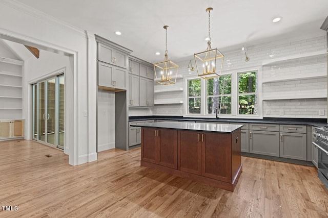 kitchen featuring backsplash, ornamental molding, hanging light fixtures, and light hardwood / wood-style floors