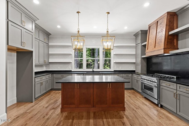 kitchen with a center island, hanging light fixtures, range with two ovens, gray cabinets, and decorative backsplash