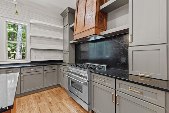 kitchen featuring gray cabinetry, double oven range, dark stone counters, decorative backsplash, and light hardwood / wood-style floors