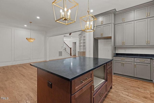 kitchen featuring a center island, an inviting chandelier, decorative light fixtures, and light wood-type flooring