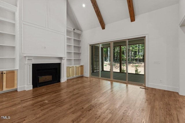 unfurnished living room featuring built in shelves, beamed ceiling, high vaulted ceiling, and hardwood / wood-style flooring