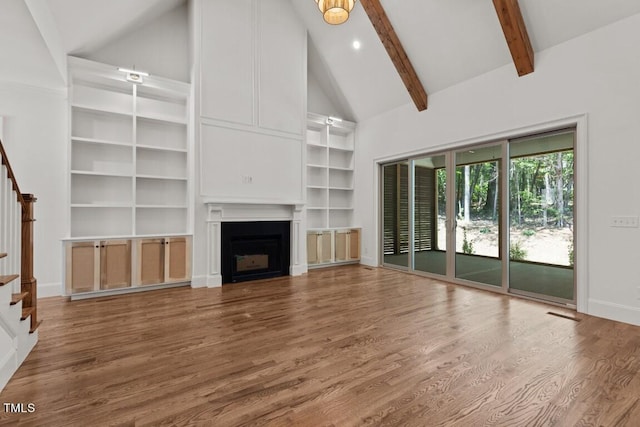 unfurnished living room with beam ceiling, hardwood / wood-style floors, and high vaulted ceiling