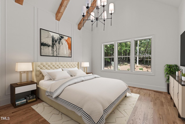 bedroom with beam ceiling, light wood-type flooring, high vaulted ceiling, and an inviting chandelier