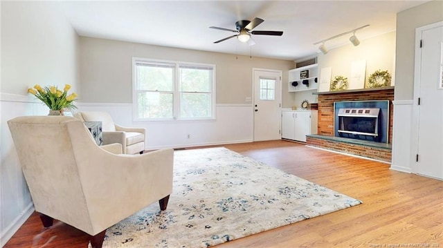 living room featuring wood-type flooring, ceiling fan, track lighting, and a fireplace