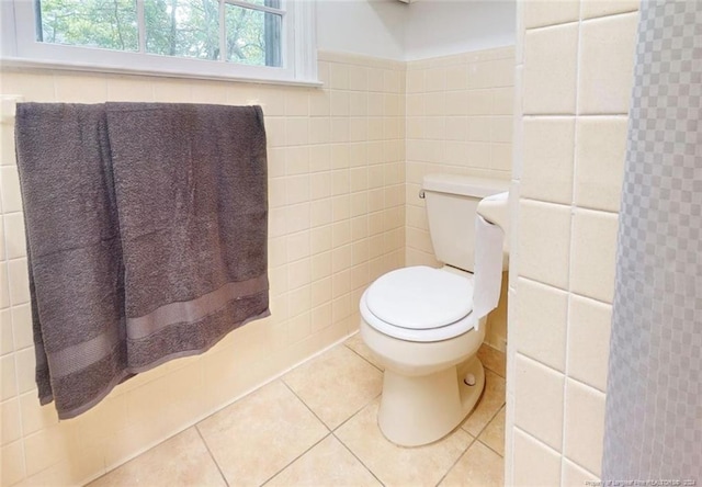 bathroom with toilet, tile floors, and tile walls