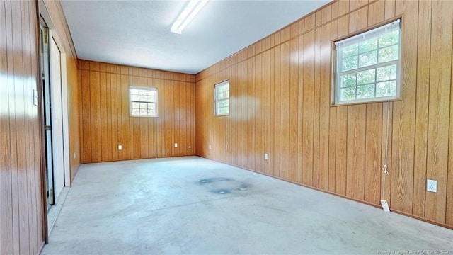 unfurnished room with concrete floors and wooden walls