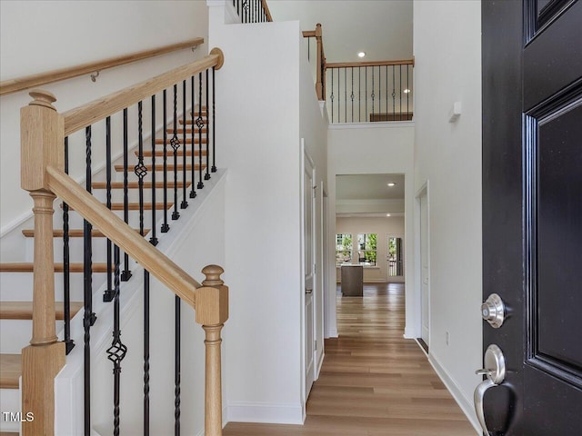 foyer entrance featuring recessed lighting, a towering ceiling, baseboards, and wood finished floors