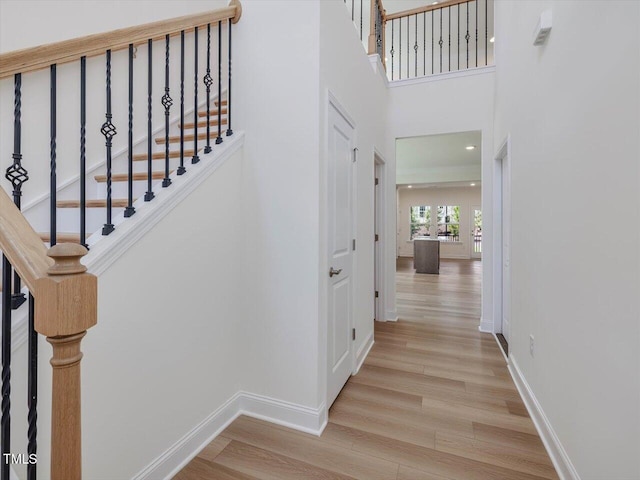 interior space featuring a towering ceiling, stairway, baseboards, and wood finished floors