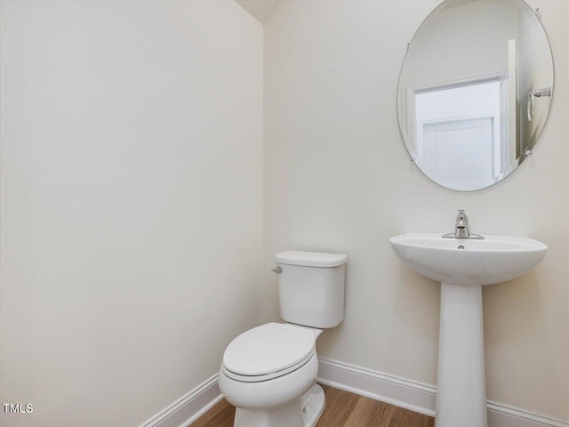 bathroom featuring toilet, baseboards, and wood finished floors