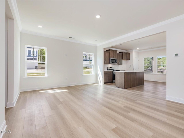 unfurnished living room featuring crown molding, light wood-type flooring, plenty of natural light, and a sink