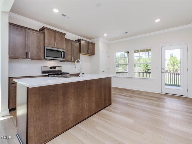 kitchen featuring light wood-type flooring, appliances with stainless steel finishes, plenty of natural light, and crown molding