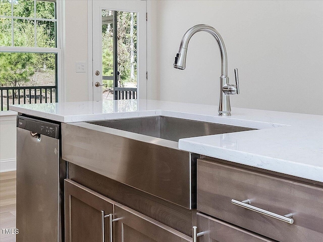 kitchen with a sink, dark brown cabinetry, stainless steel dishwasher, and wood finished floors