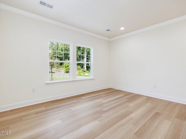 spare room featuring baseboards, visible vents, crown molding, and light wood finished floors