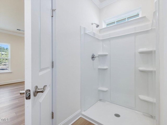 full bathroom featuring ornamental molding, walk in shower, a wealth of natural light, and wood finished floors