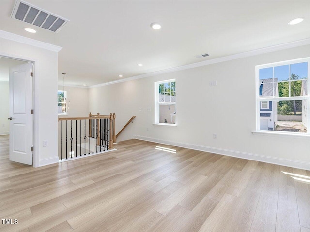 unfurnished room with light wood-style floors, visible vents, and ornamental molding