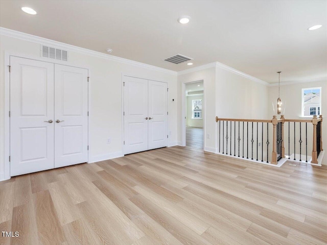 unfurnished room featuring light wood-style floors, visible vents, and ornamental molding