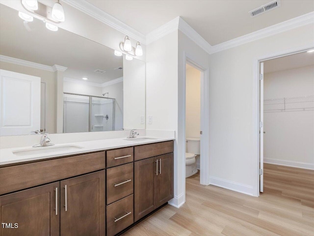 bathroom featuring toilet, a sink, visible vents, ornamental molding, and a stall shower