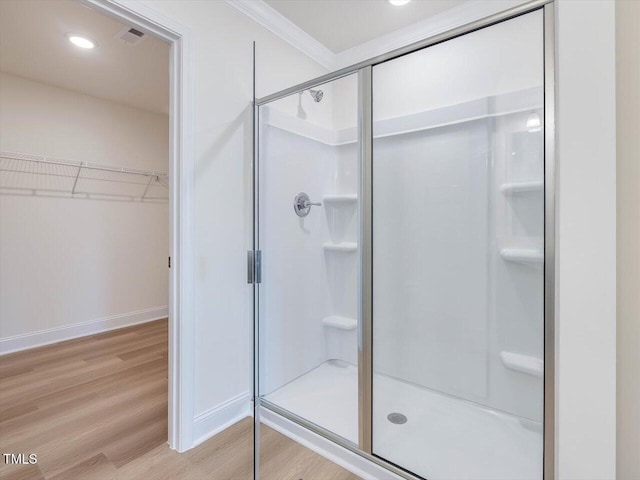 full bathroom featuring a walk in closet, visible vents, a shower stall, wood finished floors, and baseboards