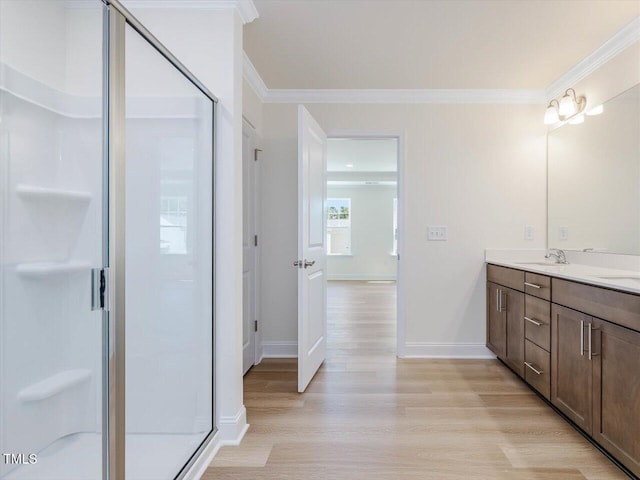 bathroom with a stall shower, crown molding, a sink, and wood finished floors