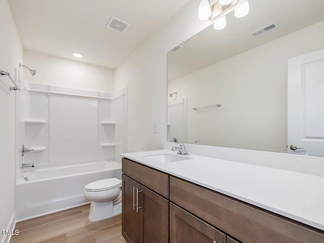 bathroom with toilet, vanity, wood finished floors, and visible vents