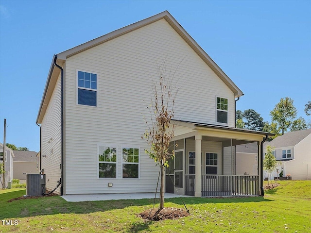 back of house featuring a sunroom, central AC unit, and a lawn