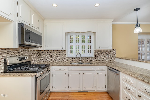 kitchen with pendant lighting, stainless steel appliances, sink, and light wood-type flooring