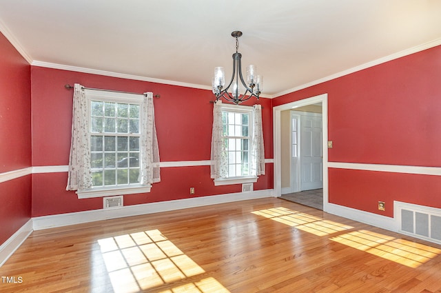 unfurnished dining area with ornamental molding, an inviting chandelier, and hardwood / wood-style floors