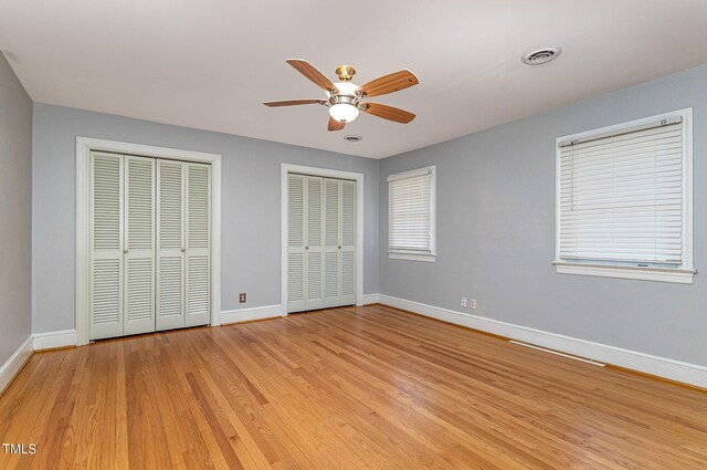 unfurnished bedroom featuring light hardwood / wood-style floors, ceiling fan, and two closets