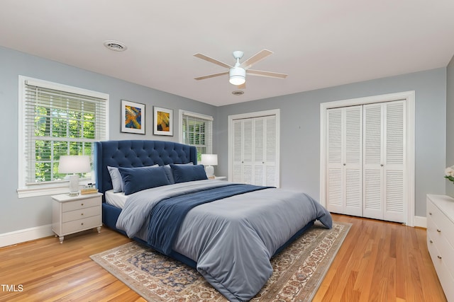 bedroom with ceiling fan, light hardwood / wood-style floors, and multiple closets