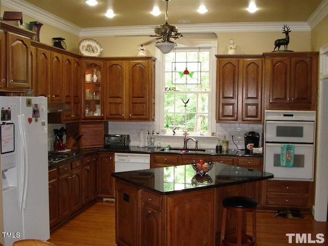 kitchen with a kitchen island, white appliances, tasteful backsplash, sink, and light wood-type flooring