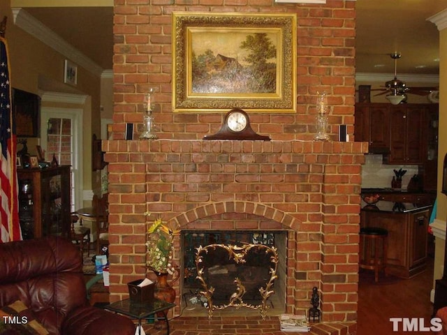 living room featuring brick wall, crown molding, ceiling fan, and a fireplace