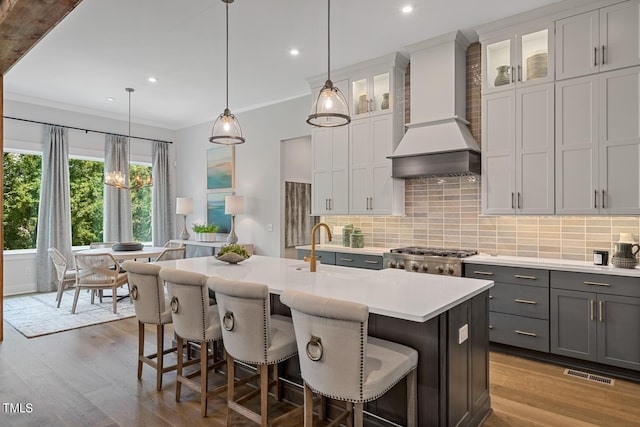 kitchen featuring hanging light fixtures, backsplash, premium range hood, and stove