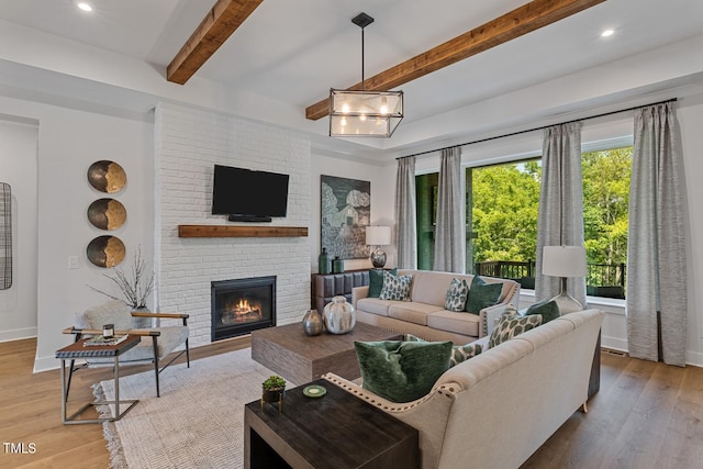 living room featuring hardwood / wood-style flooring, brick wall, beamed ceiling, and a fireplace