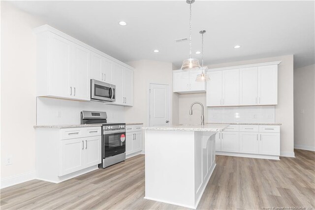 kitchen featuring a center island with sink, light wood-type flooring, white cabinets, and stainless steel appliances